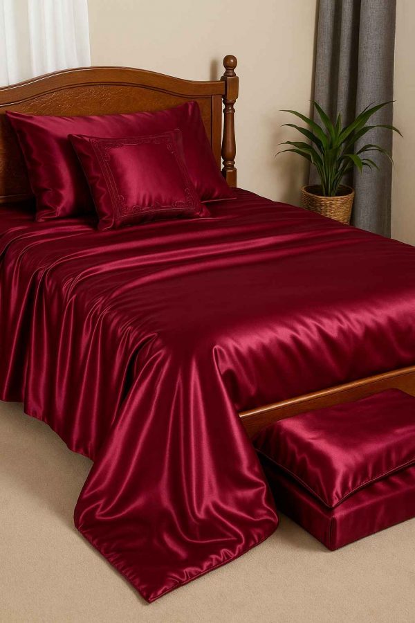 A photograph showcases a bedroom with a bed dressed in a luxurious satin bedcover set in deep burgundy