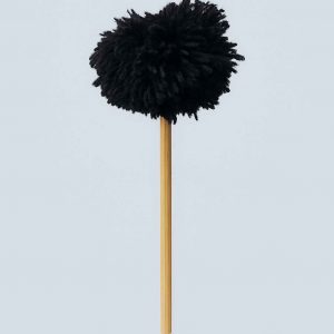 Studio photo of a handmade black yarn pompom flower on a slender wooden stem