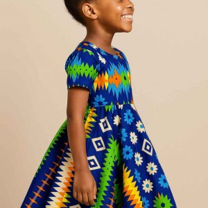 Young African girl wearing a vibrant multi-pattern kitenge flare dress, right profile view