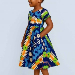 Young African girl in a multi-pattern kitenge flare dress smiling joyfully in side view
