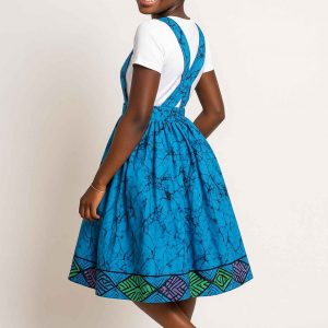 Smiling African girl modeling a vibrant kitenge suspender skirt in an angled pose