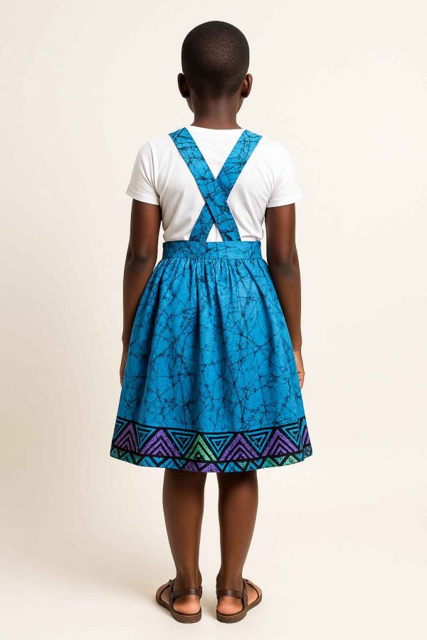 Back view of a young African girl wearing a kitenge suspender skirt with crossed suspenders