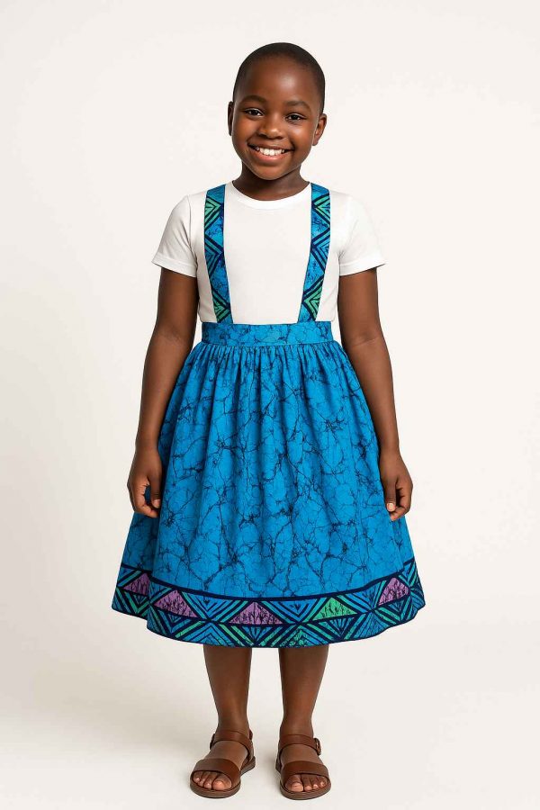 Front view of a young African girl wearing a kitenge suspender skirt and white shirt