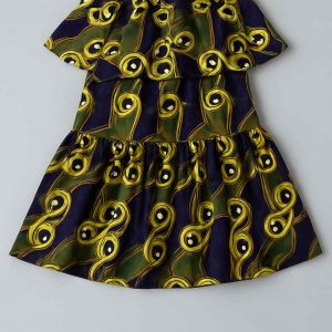 Bottom view of a girls’ African peplum dress showing two gathered skirt tiers in bold yellow, green, and purple print