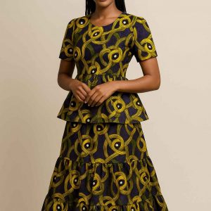 Young African girl modeling a tiered peplum kitenge dress in a neutral studio setting with soft lighting