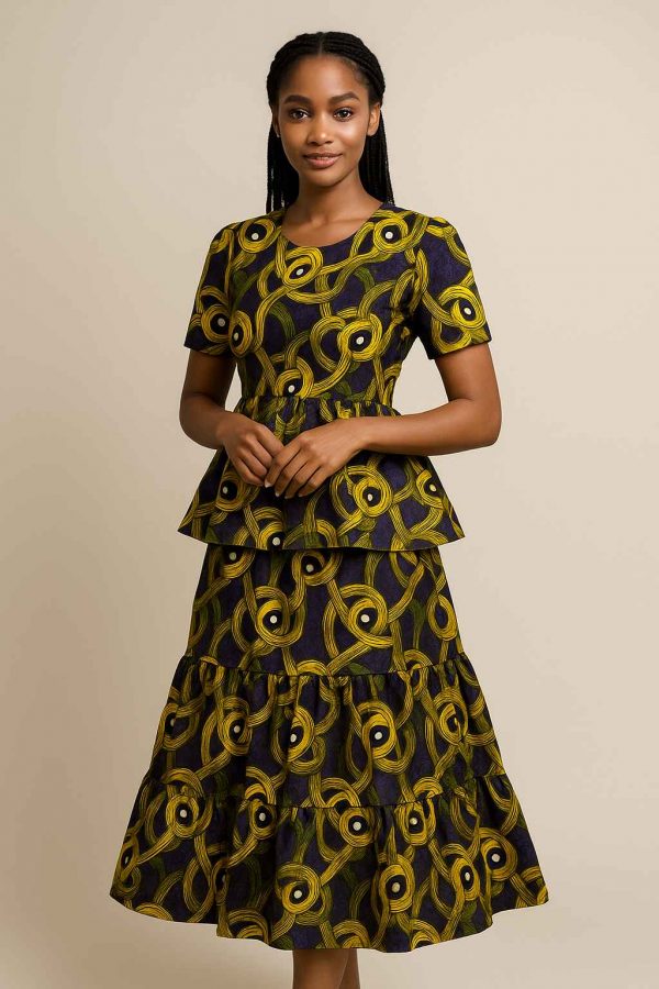 Young African girl modeling a tiered peplum kitenge dress in a neutral studio setting with soft lighting