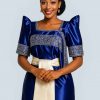 Elegant Ugandan woman wearing blue Gomesi with white sash front view