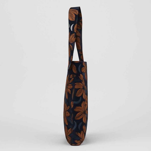 Side studio view of a handmade African print tote bag showing thin profile and double-stitched strap