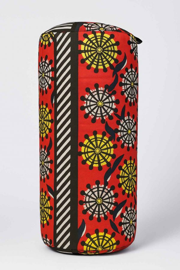 Front-facing studio image of an African print bolster cushion with red, yellow, and black patterned fabric