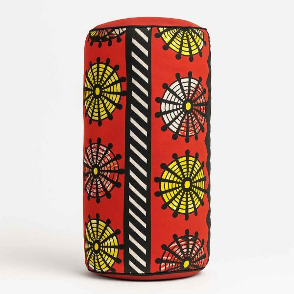 Side studio view of an African print bolster cushion showing rounded edge and vibrant African fabric