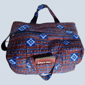 Angled view of GraceTrail Kitenge Travel Holdall in blue and brick-red African print