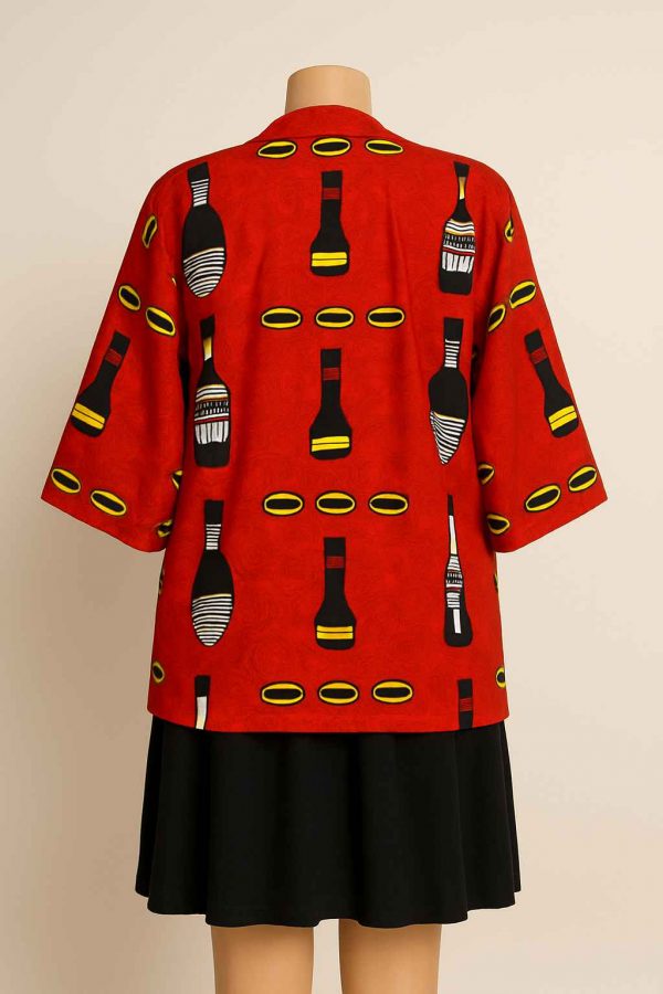 Back view of a red African Kitenge jacket with medium sleeves, styled over a dark skirt and displayed on a mannequin.