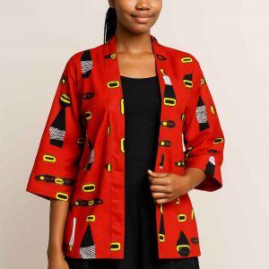 African woman modeling a red African kitenge jacket with medium sleeves and a dark skirt, standing gracefully in a clean studio setting.