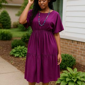 Young African woman wearing a royal purple tiered midi dress while standing outdoors in soft natural light