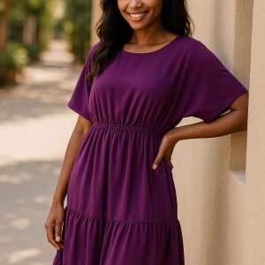 Young African woman in a royal purple modest midi dress standing gracefully in a sunlit outdoor walkway