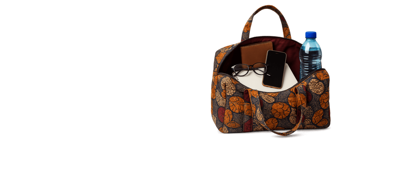 A vibrant African kitenge tote bag opened to reveal a leather wallet, eyeglasses, smartphone, and water bottle — neatly arranged to showcase function and fashion